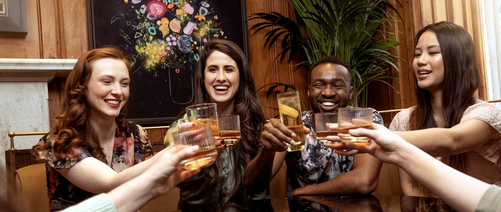 Quatre amis attablés lèvent leur verre au restaurant.