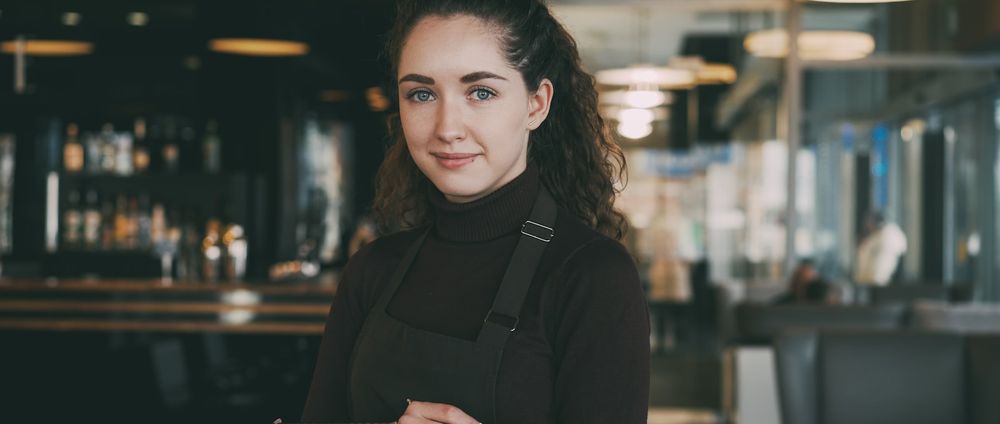 Une serveuse en tablier dans la salle d'un restaurant.