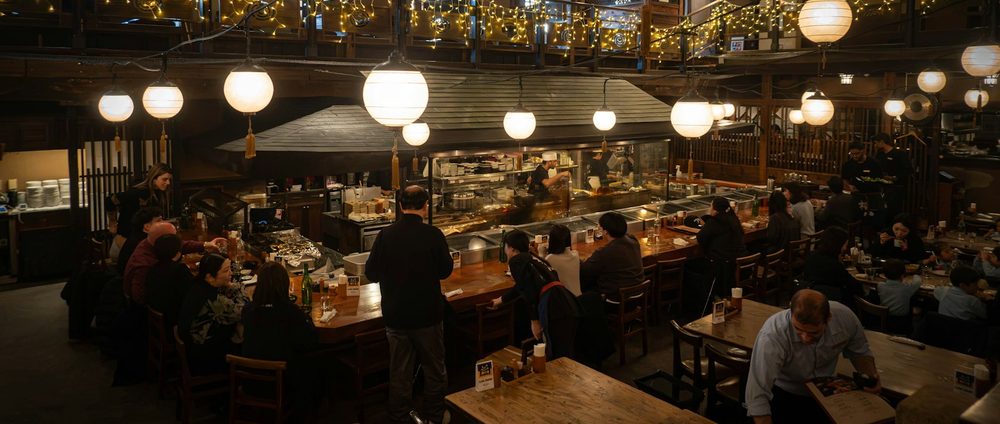 Une salle de restaurant pleine, vue d'en haut, avec ses tables en bois pendant le service.