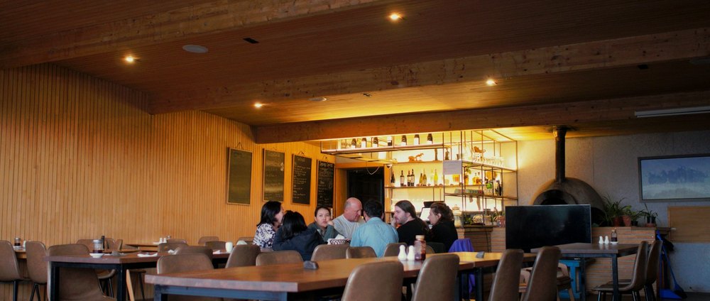 Une salle de restaurant avec des clients attablés, vue depuis l'entrée.