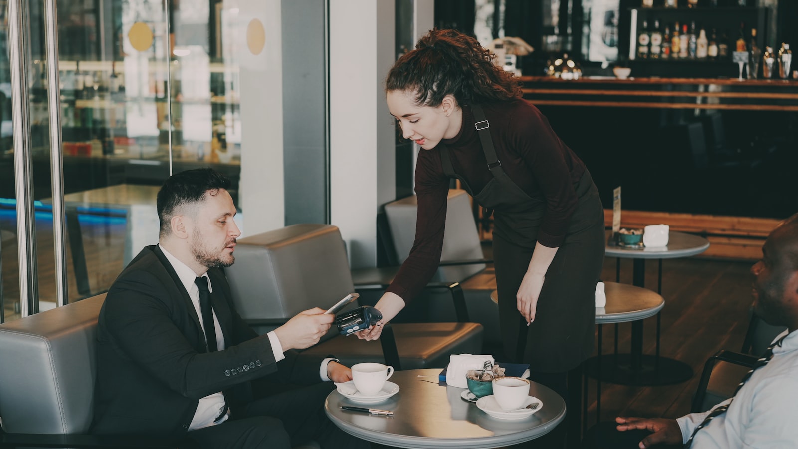 Une serveuse encaisse un client à table avec un terminal de paiement