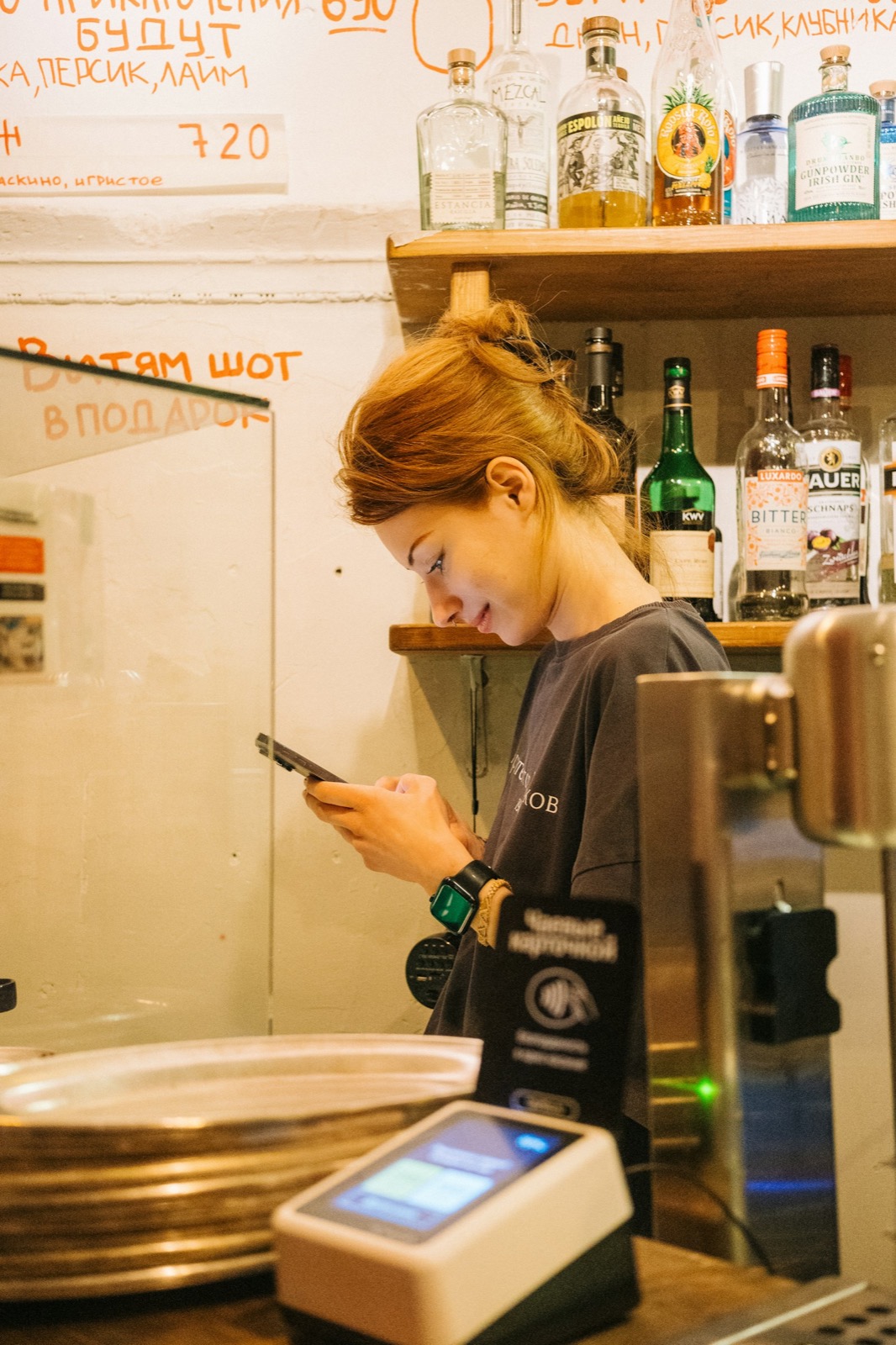 Une restauratrice au téléphone derrière son comptoir, en plein service